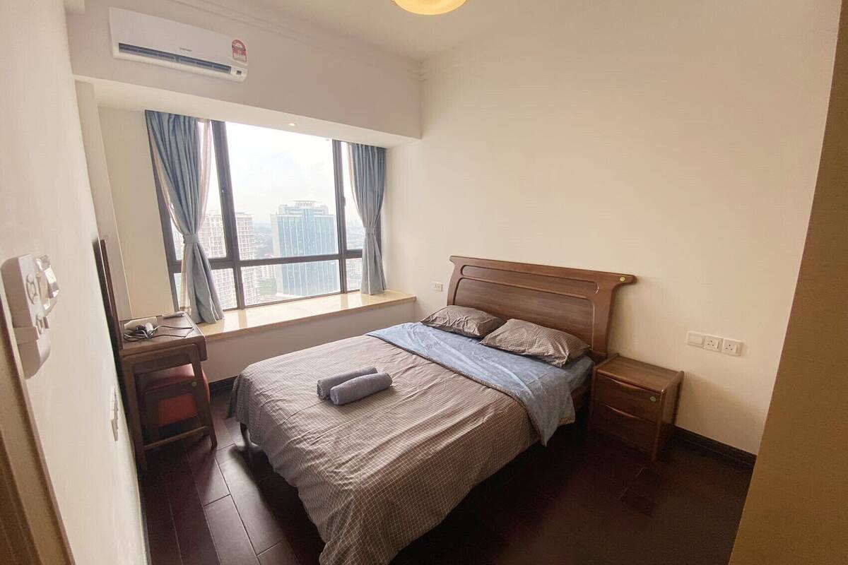 Une chambre à coucher avec un lit, une table de chevet, un bureau et une fenêtre avec des rideaux.