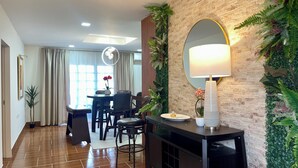 Habitació d'hotel moderna amb zona de menjador, un gran mirall i una paret decorativa amb plantes.