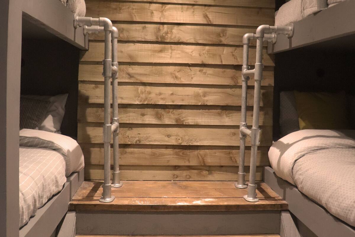 A bunk bed room with metal ladders and wooden walls.