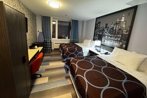 A hotel room with two beds, a desk, a chair, a window with curtains, and a cityscape view. - Super 8 By Wyndham Brooklyn Fulton Street (Brooklyn)