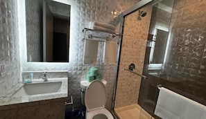 Une salle de bain équipée d’un lavabo, de toilettes et d’une douche à parois de verre.