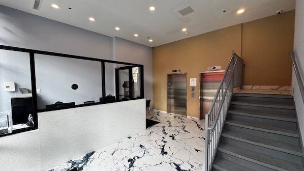A hotel lobby with a reception desk, two elevators, and a staircase. - Super 8 By Wyndham Brooklyn Fulton Street (Brooklyn)