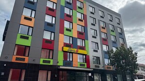 A multi-story hotel with colorful facades, a prominent 'Super8' sign, and a tree in the foreground.