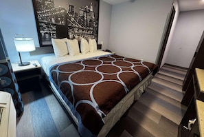 A hotel room with a bed, a nightstand, a lamp, a phone, and a cityscape wall art. - Super 8 By Wyndham Brooklyn Fulton Street (Brooklyn)