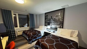 Une chambre d’hôtel avec deux lits, un bureau, une chaise, une fenêtre avec des rideaux et un tableau représentant un paysage urbain accroché au mur.