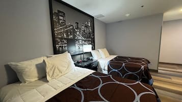 A modern hotel room with a large bed, a bedside table with a lamp, and a cityscape artwork on the wall.