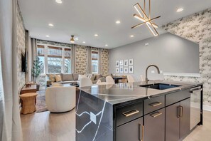 A modern kitchen with a large island, built-in appliances, and a dining area with a sofa and chairs. - Luxe Downtown Home • DT ~2m • Rooftop • Fireplace (Nashville)