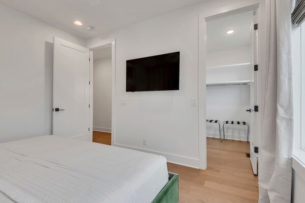A bedroom with a bed, a TV mounted on the wall, and a closet with a mirror.
