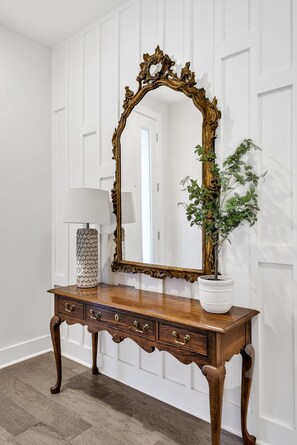 A wooden console table with a large ornate mirror, a potted plant, and a lamp. - Luxe Downtown Home • Rooftop • Fireplace • DT ~2m (Nashville)