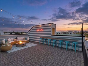 A rooftop terrace with a fire pit, seating area, bar stools, and a neon sign. - Luxe Downtown Home • Rooftop • Fireplace • DT ~2m (Nashville)