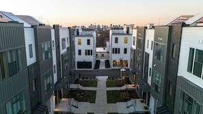 A modern building with a central courtyard, multiple floors, and a city skyline in the background.