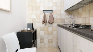 A modern kitchen with a gas stove, a sink, and a small dining area with a chair and table.