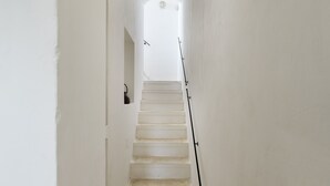 A narrow, white-walled stairway leading to a landing with a light fixture above.