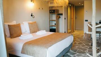 A neatly made bed with a beige blanket and pillows, a hanging light fixture, and a stone-patterned floor.