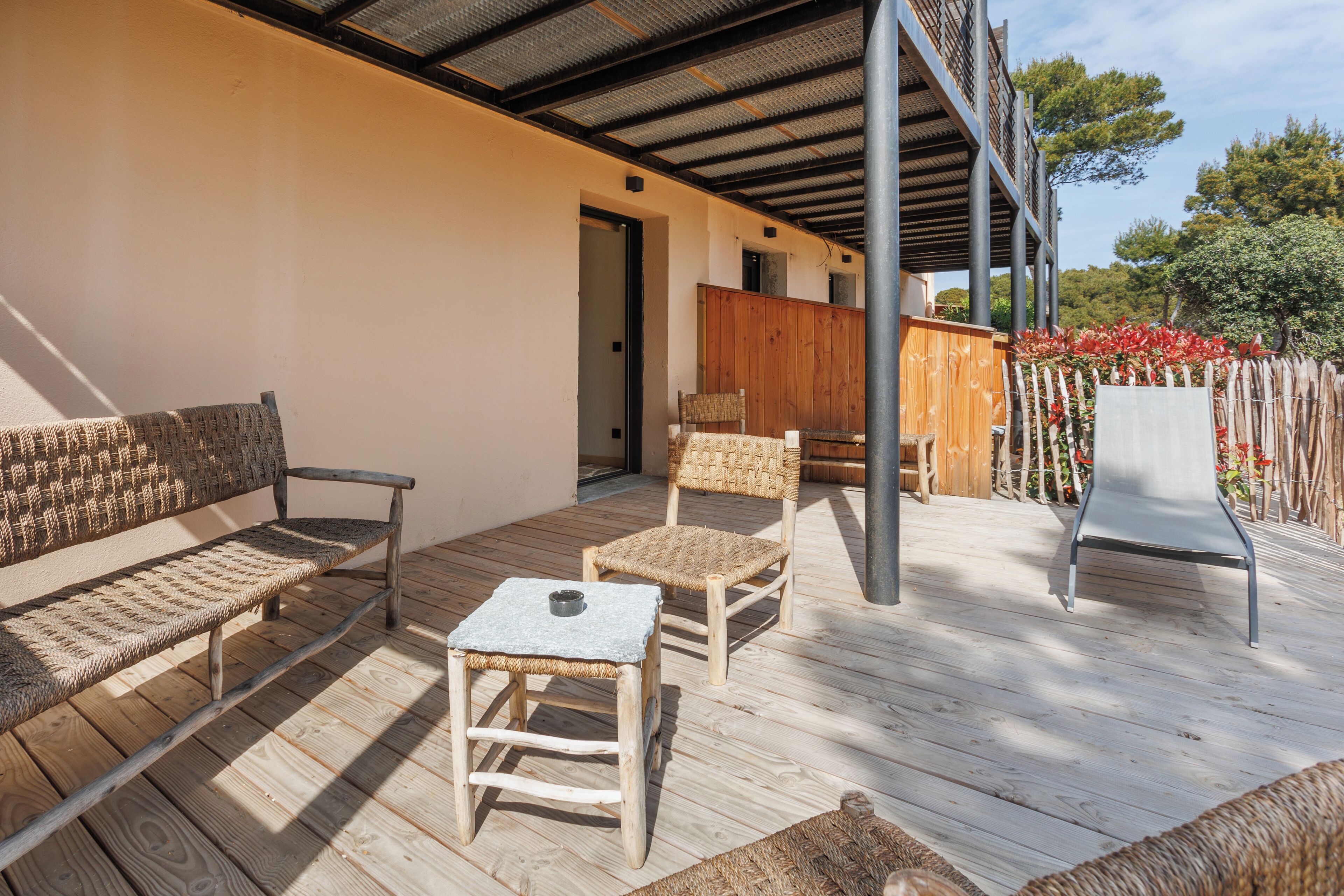 A wooden deck with a bench, two chairs, and a small table.