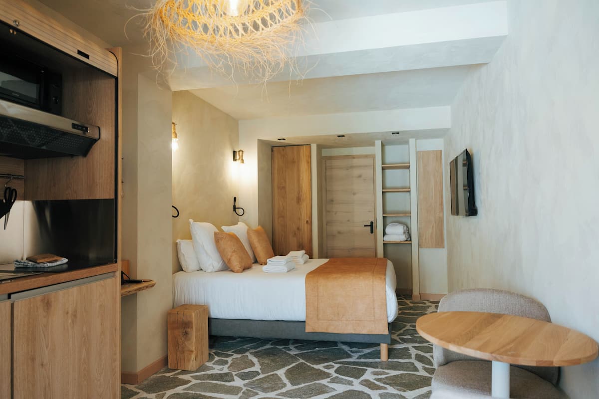 Ein modernes Hotelzimmer mit einem Bett, Holzmöbeln, einem kleinen Tisch und einem Boden mit Steinmuster.