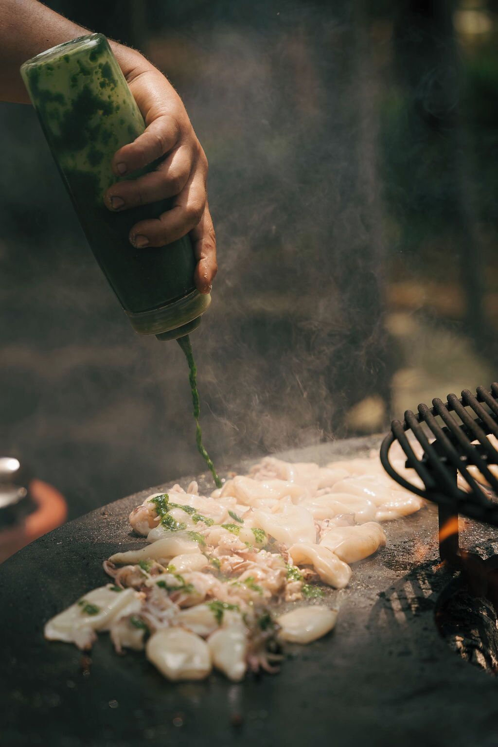 A person grilling seafood on an outdoor grill with a visible grill tool.