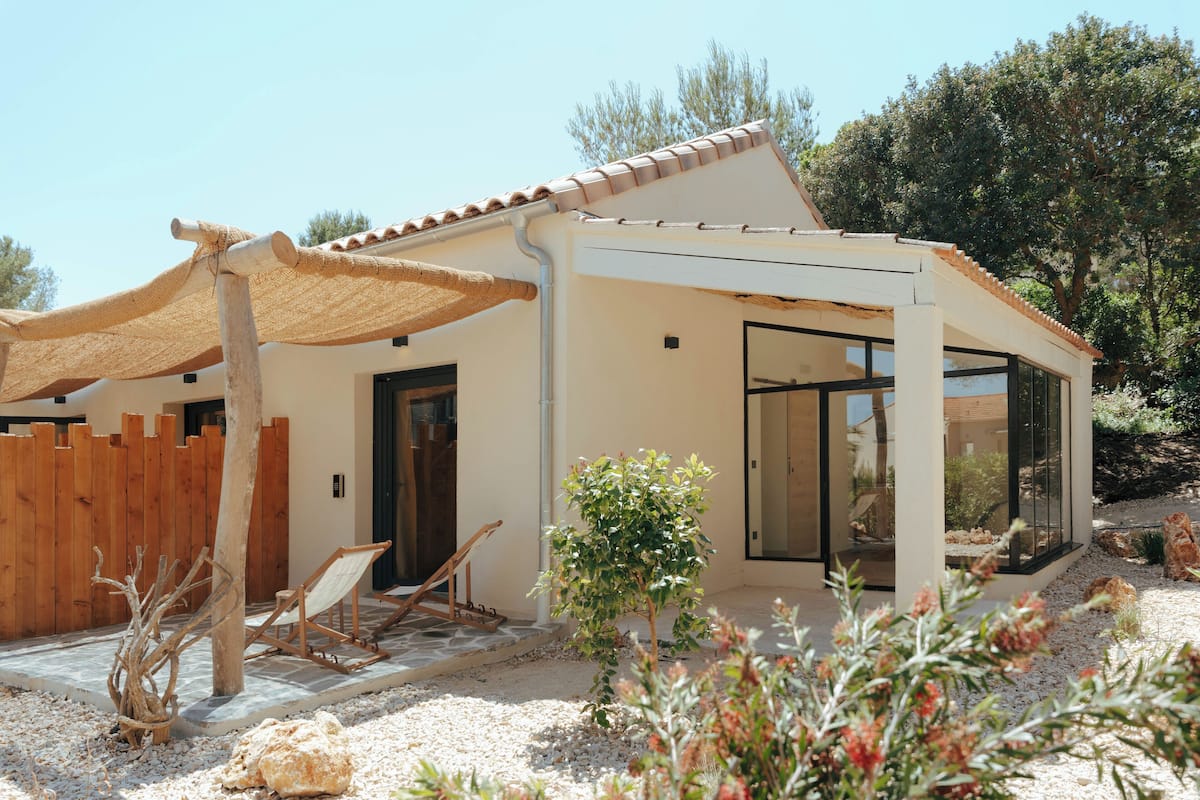 Ein modernes Haus mit Terrasse, Holzzaun und einem kleinen Baum.