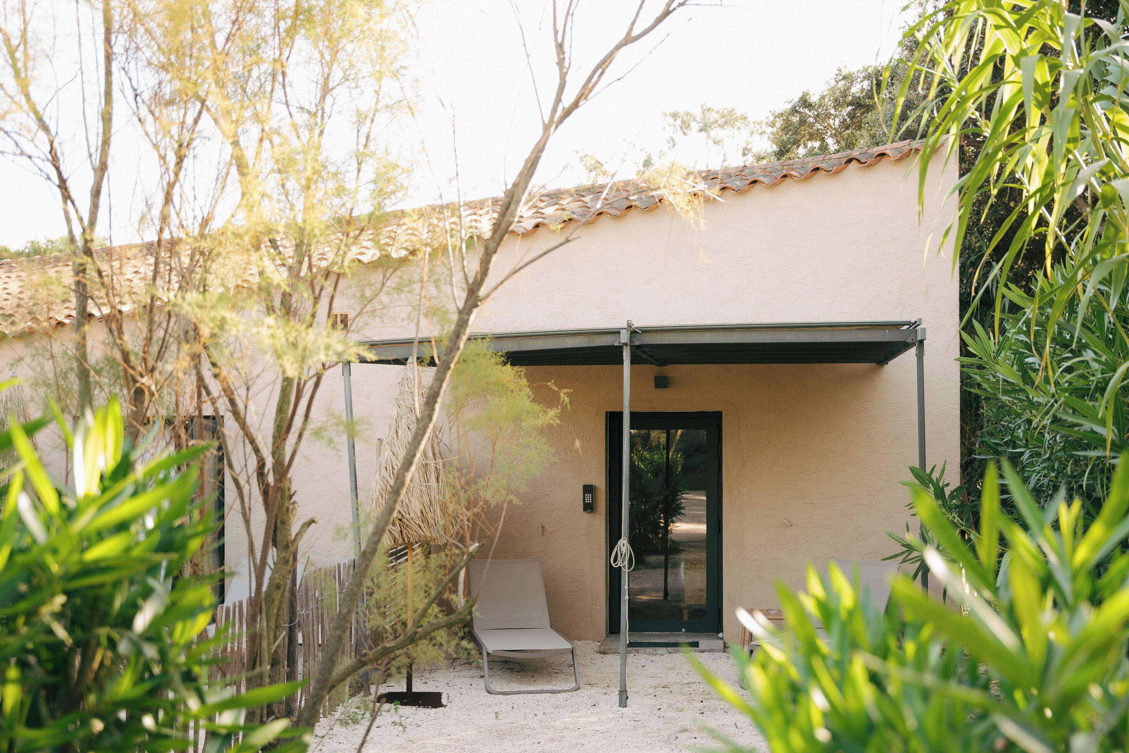 A building with a beige exterior, a covered patio area, and a door with a security camera.