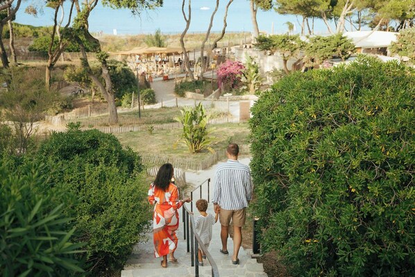 Una famiglia cammina lungo una scalinata in pietra immersa nel verde.