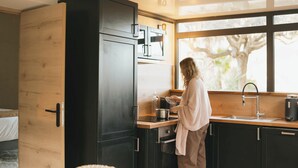 Een moderne keuken met donkere kasten, een houten aanrechtblad en een groot raam.