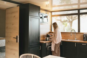 Een moderne keuken met donkere kasten, een houten aanrechtblad en een groot raam.