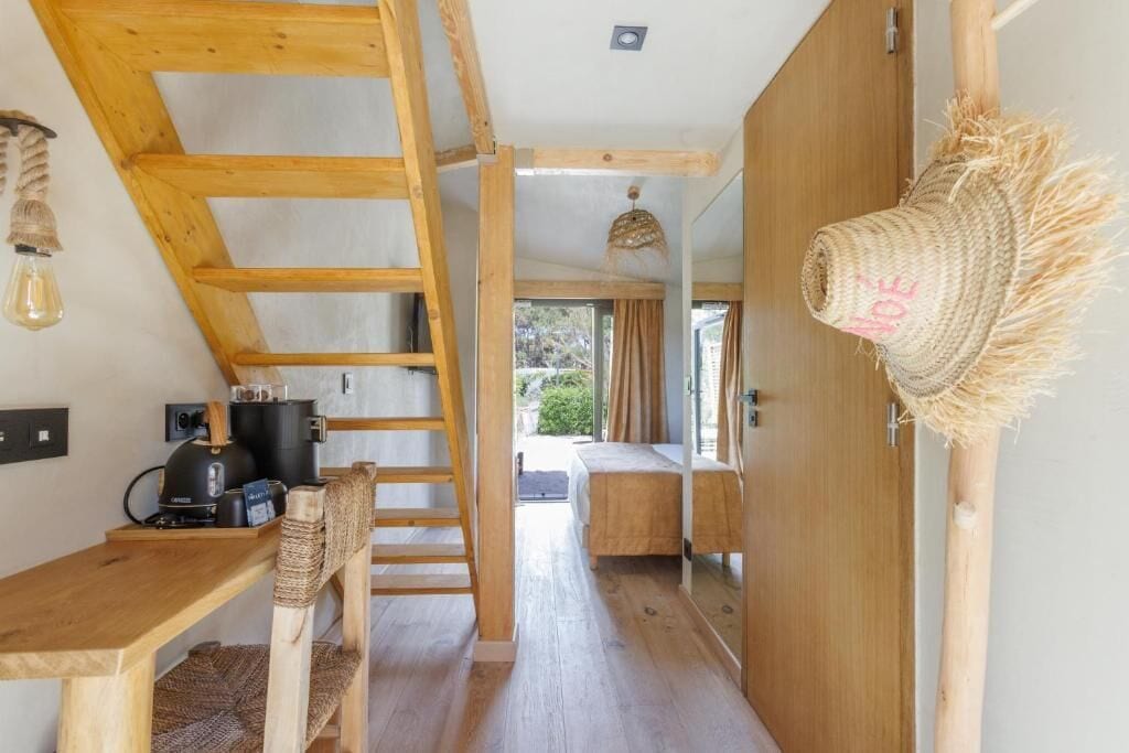 Interior em madeira com um mezanino para dormir, uma cozinha com máquina de café e uma cesta trançada na parede.