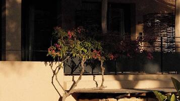 Un edificio con base de piedra, cerca de madera y un árbol con flores rosadas.