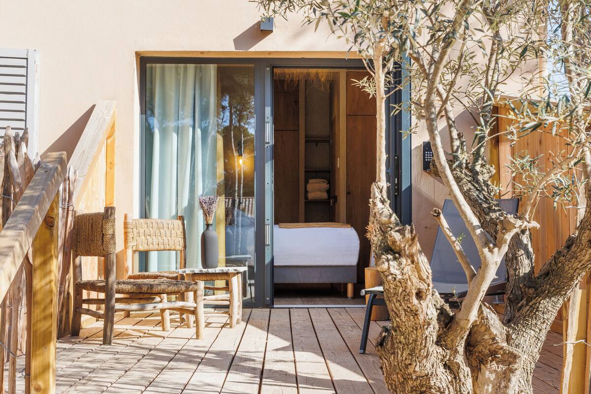 Eine Holzterrasse mit einem Bett, einem Stuhl und einem Tisch.
