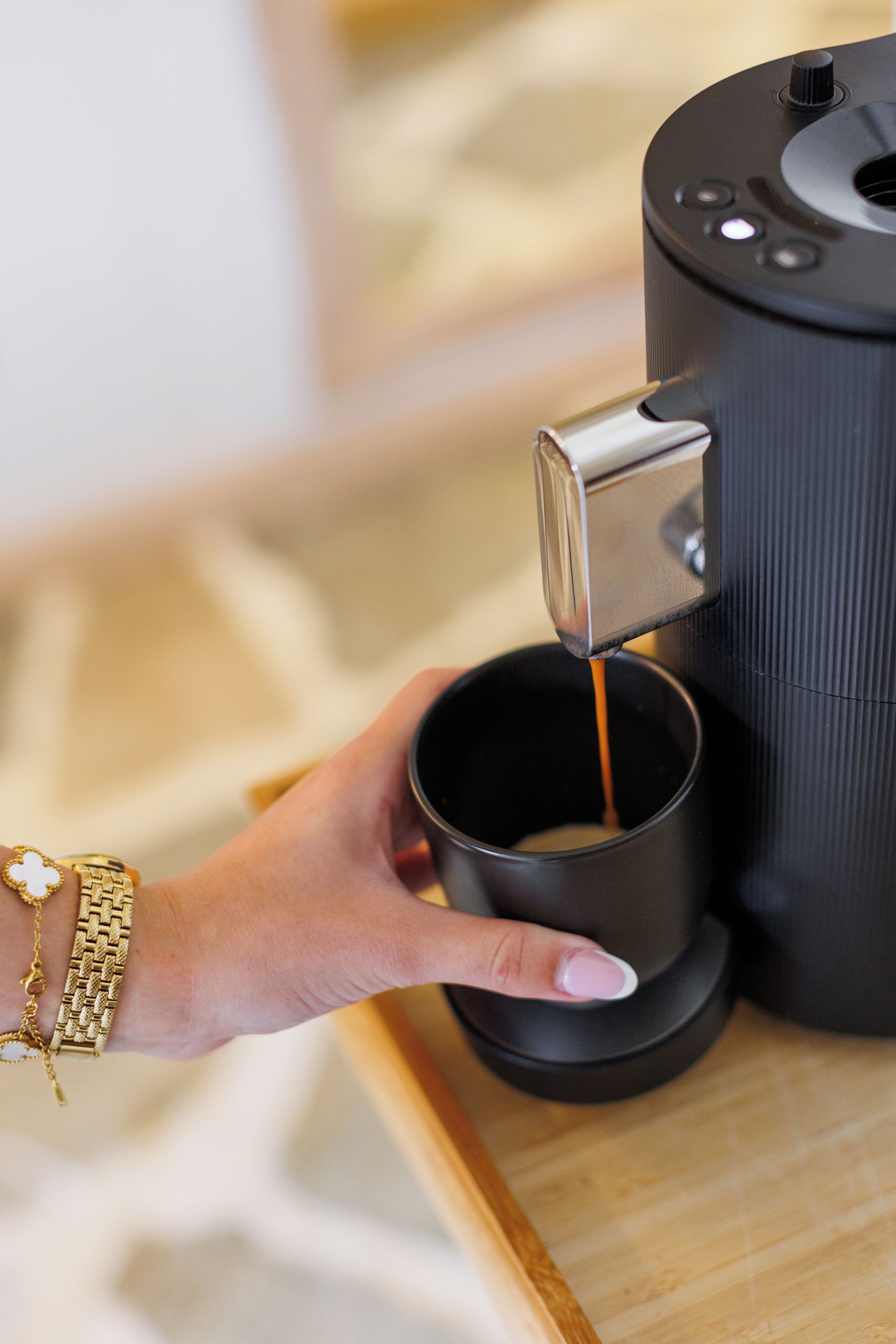 Eine Hand hält eine Tasse unter einer Kaffeemaschine, die Kaffee ausgibt.