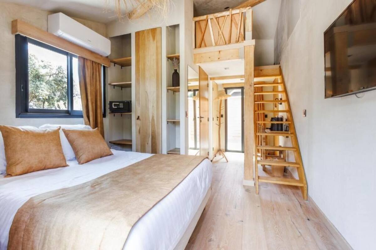 Ein Schlafzimmer mit einem Bett, Holzregalen, einer Treppe und einem an der Wand befestigten Fernseher.