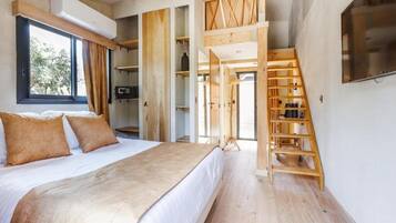 A bedroom with a bed, wooden shelving, a staircase, and a TV mounted on the wall.