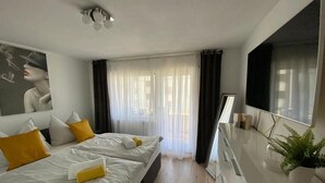 A hotel room with a bed, a desk, a mirror, and a window with curtains. - Stylische Wohnung mit Traumausblick in Dornbirn (Dornbirn)