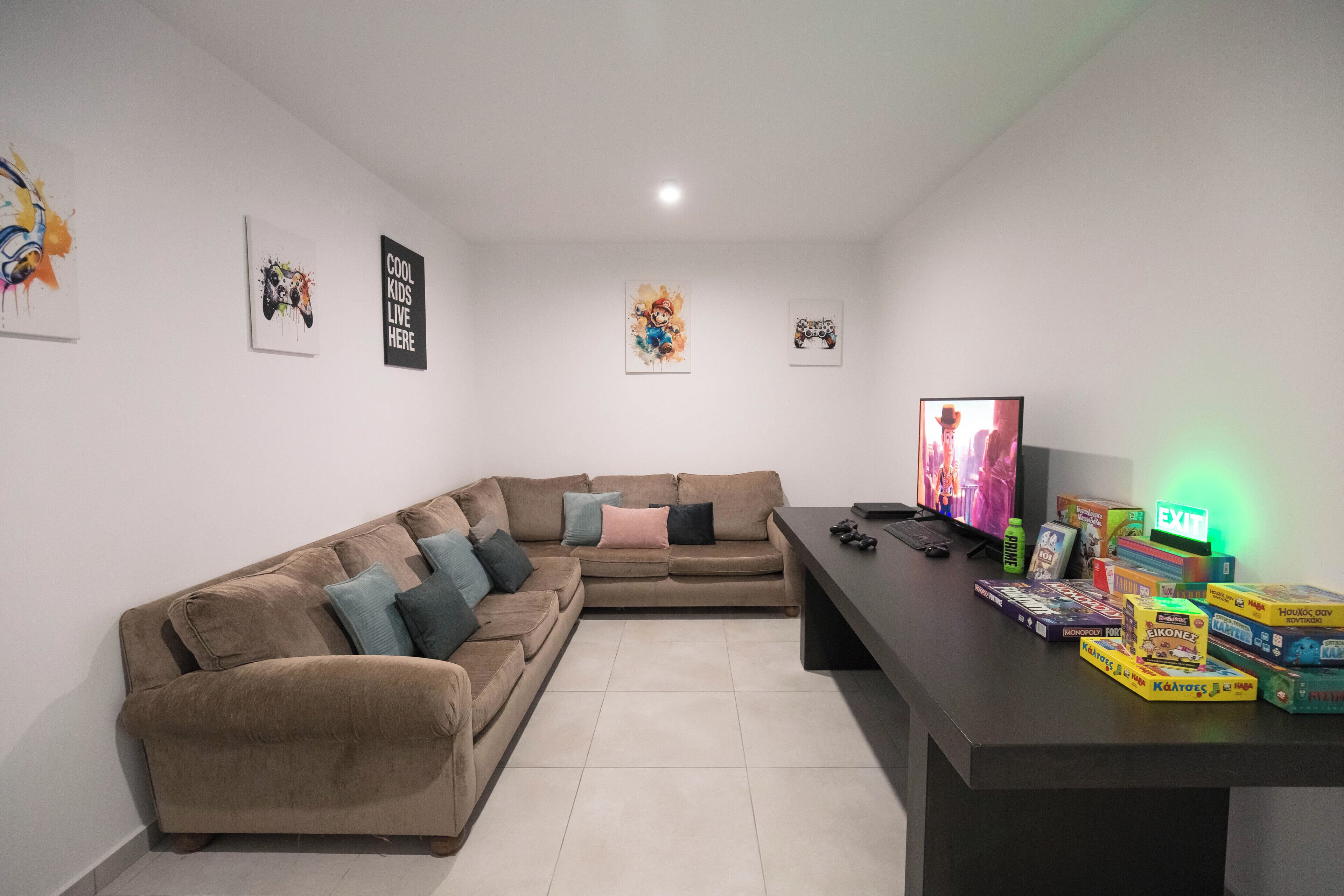 A living room with a brown sectional sofa, a flat-screen TV, and various board games on a table.