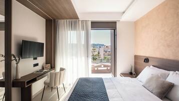 Een moderne hotelkamer met een groot bed, een bureau met een flatscreen-tv, een stoel en uitzicht op de stad.