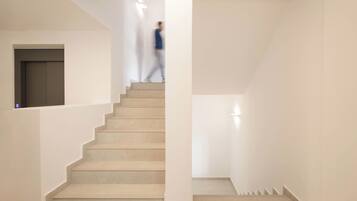 Una escalera moderna con un diseño minimalista, paredes blancas y un suelo en tonos neutros.