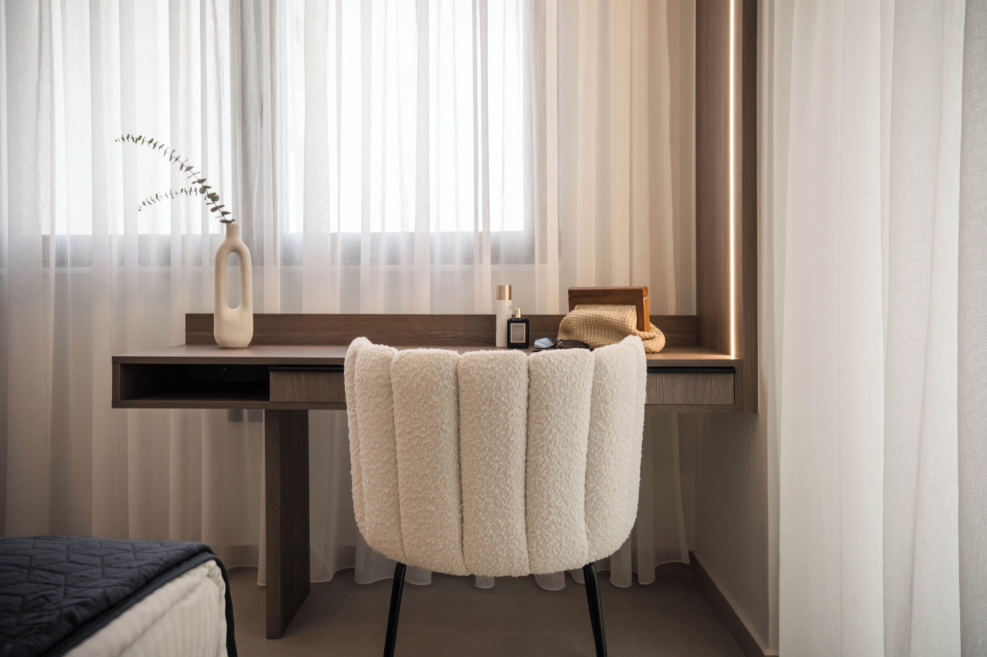 Quarto de hotel moderno com uma janela grande, uma secretária com cadeira e uma cama.