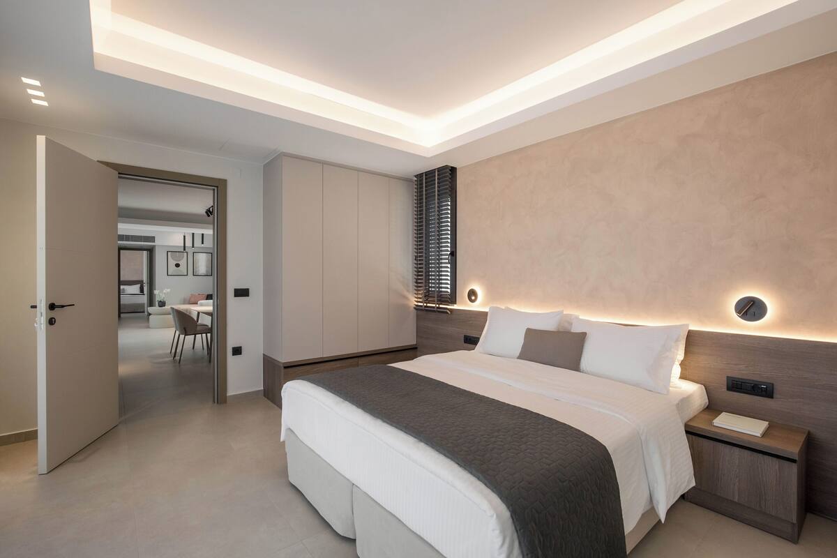 A modern bedroom with a large bed, bedside tables, and a built-in wardrobe.