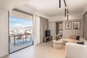 Ένα σύγχρονο σαλόνι με μπαλκόνι, τηλεόραση επίπεδης οθόνης και καναπέ.