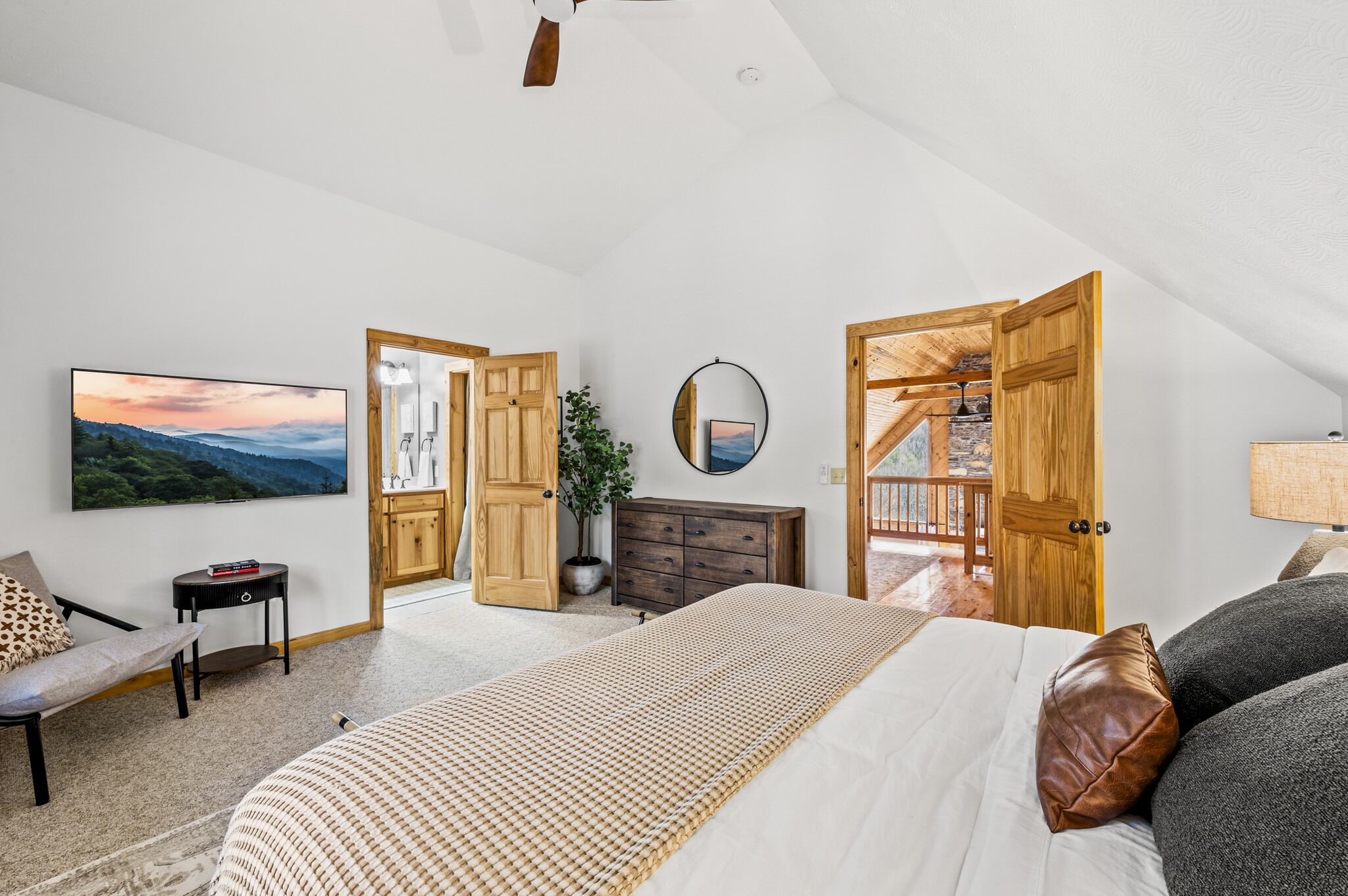 Un'ampia camera da letto con un letto grande, un'armadiatura in legno, una scrivania e una sedia. È presente un'ampia finestra con vista sull'esterno.