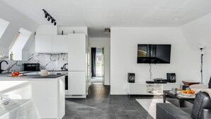 Eine moderne Küche mit weißen Schränken, einer Marmor-Spritzschutzleiste und einem Essbereich mit Tisch und Stühlen.