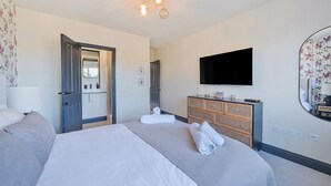 Ein Hotelzimmer mit einem Bett, einem Fernseher, einem Spiegel und einem Schminktisch.