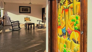 A spacious lobby with a wooden door labeled "Ayuda," a tiled floor, and several rocking chairs. - Hotel Villas Ponto Holbox (Isla Holbox)