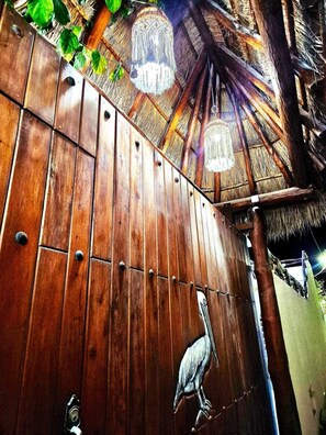 A wooden gate with a peacock sculpture, a thatched roof, and a wooden fence. - Hotel Villas Ponto Holbox (Isla Holbox)