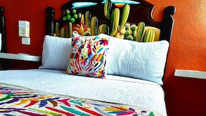 A bed with a colorful striped bedspread, a cactus-themed headboard, and a white pillow. - Hotel Villas Ponto Holbox (Isla Holbox)
