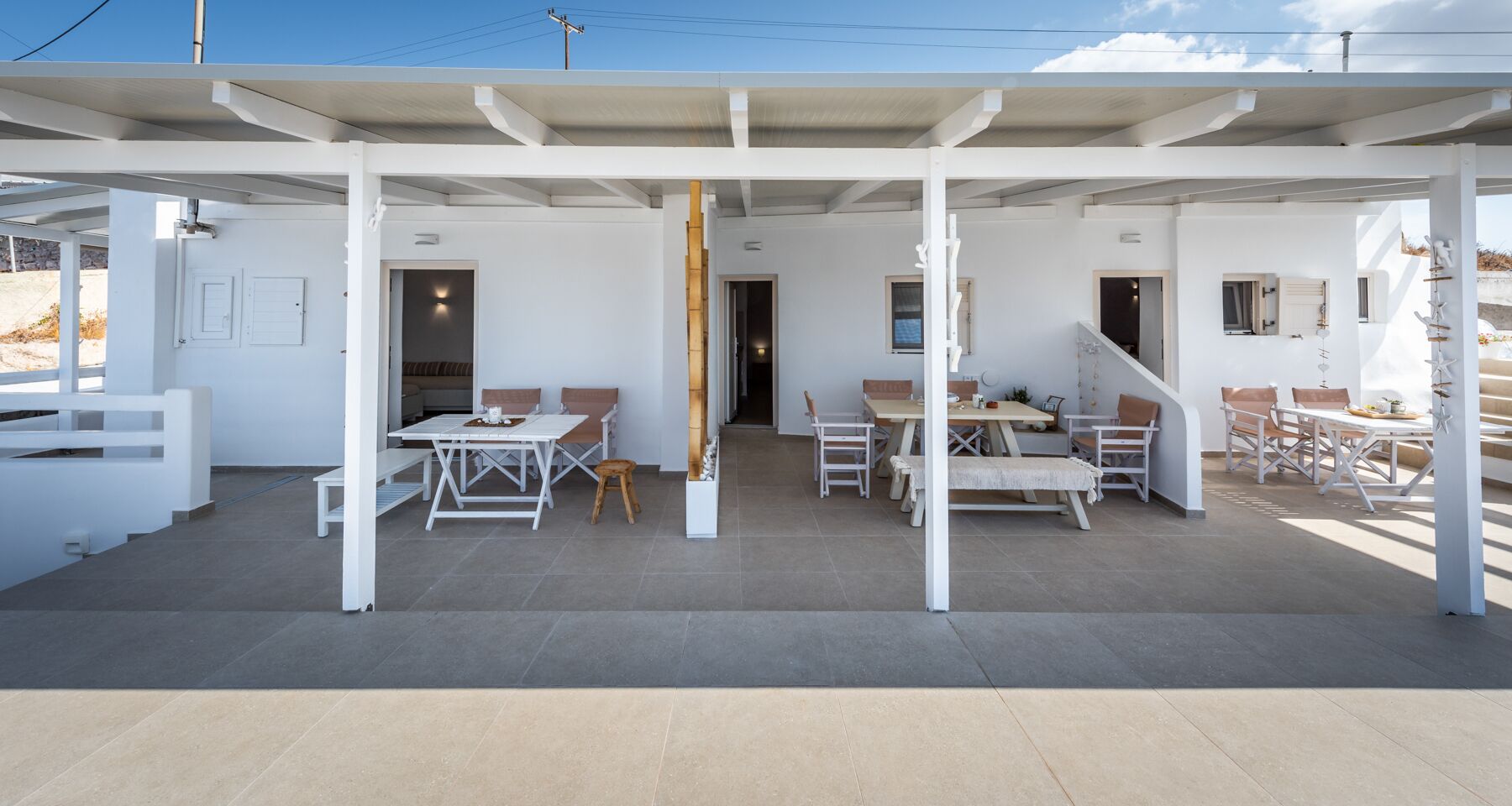 A covered outdoor area with multiple seating arrangements, including tables and chairs, and a staircase leading to an upper level.