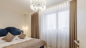Un dormitorio con cama, candelabro, cortinas y vistas por la ventana.