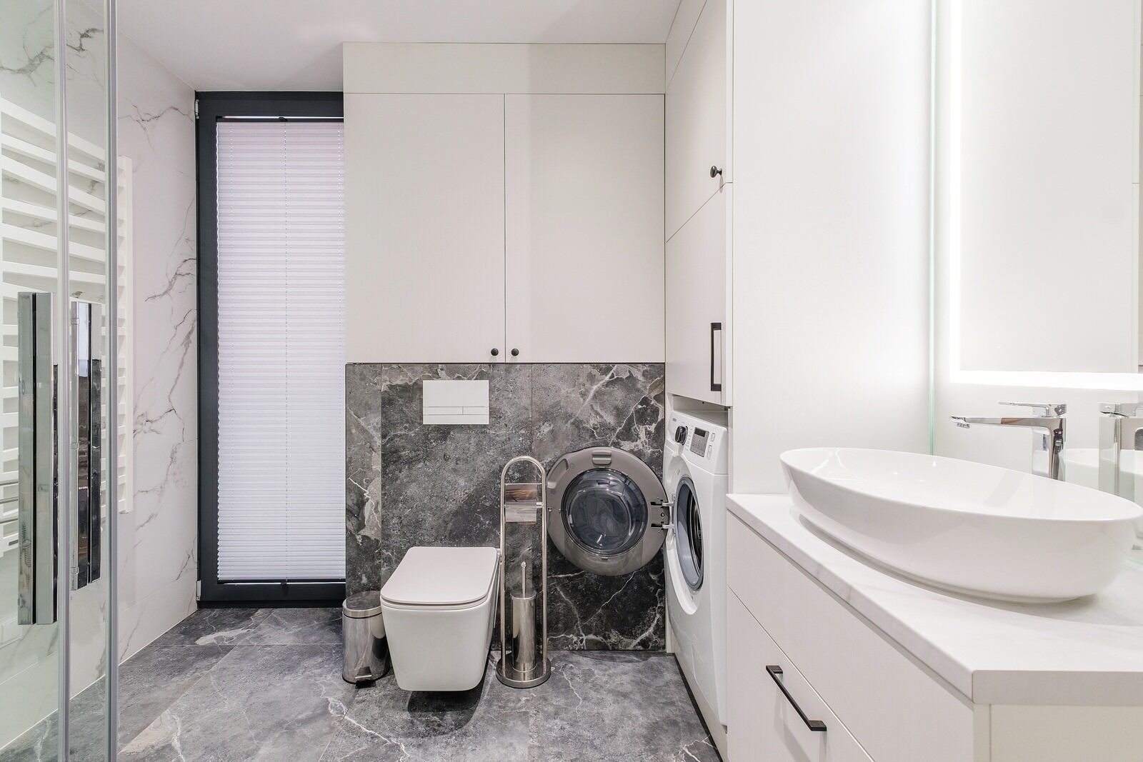 A modern bathroom with a toilet, washing machine, and sink.