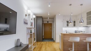 Una cocina moderna con armarios blancos, encimera de madera e iluminación colgante.