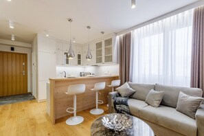 Un salon moderne avec un canapé, une table basse et un coin cuisine doté d’un bar.